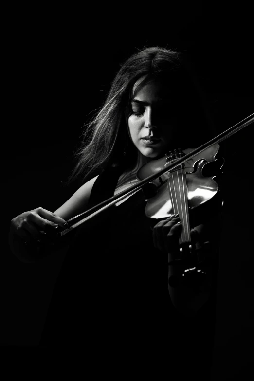 a black and white image of a female with long hair holding a violin