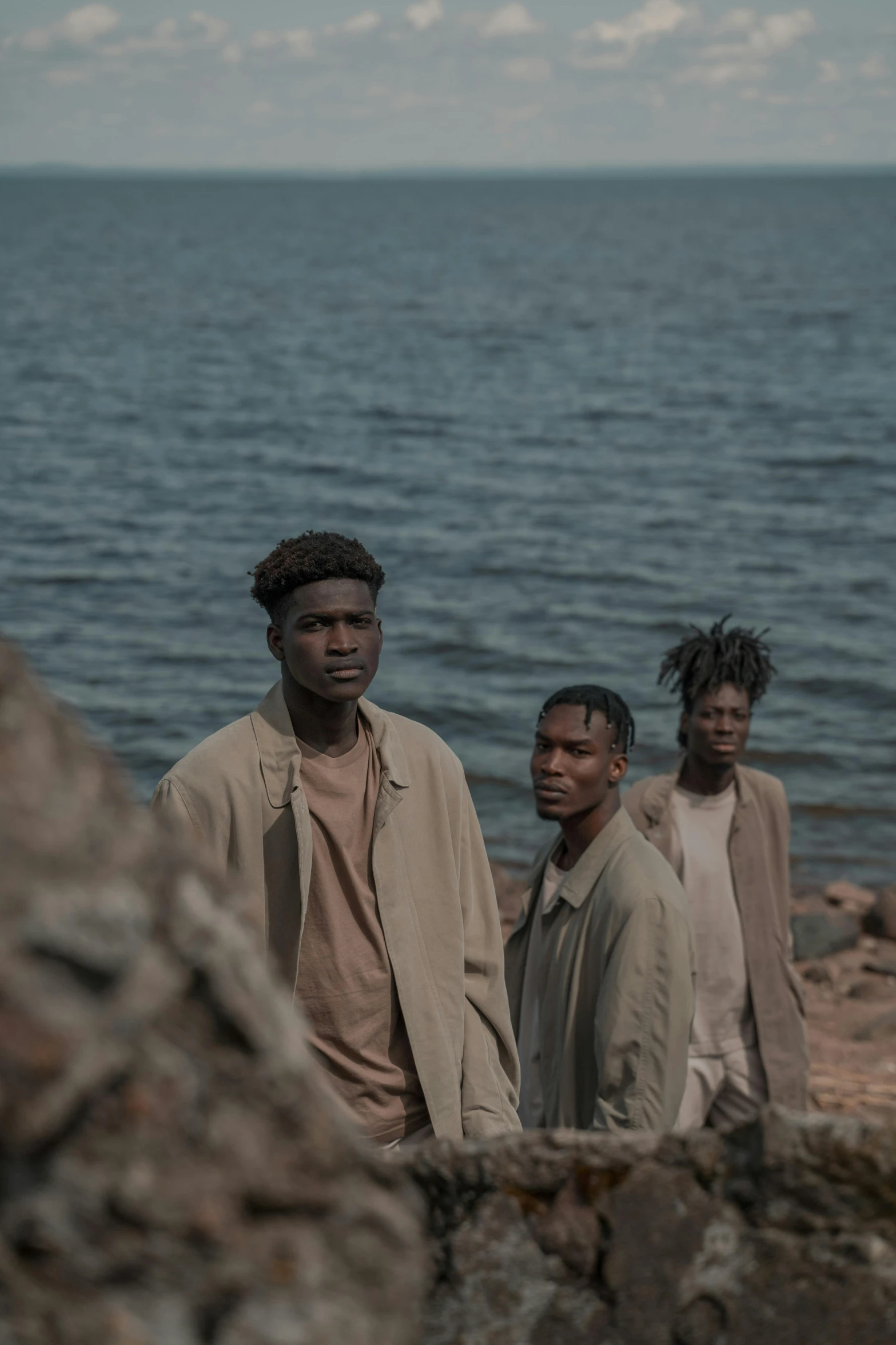 three people standing on the rocks near a body of water