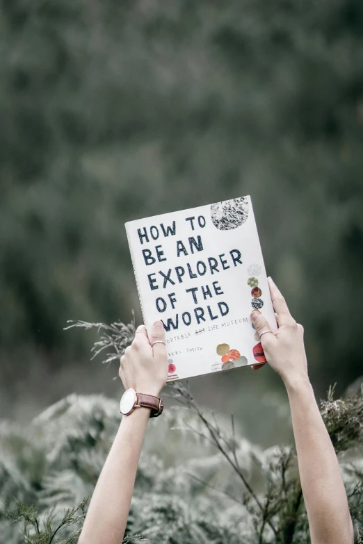 person holding sign stating how to be an explorer of the world