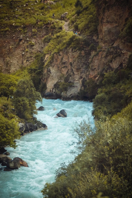 the view of a blue water rapids next to trees