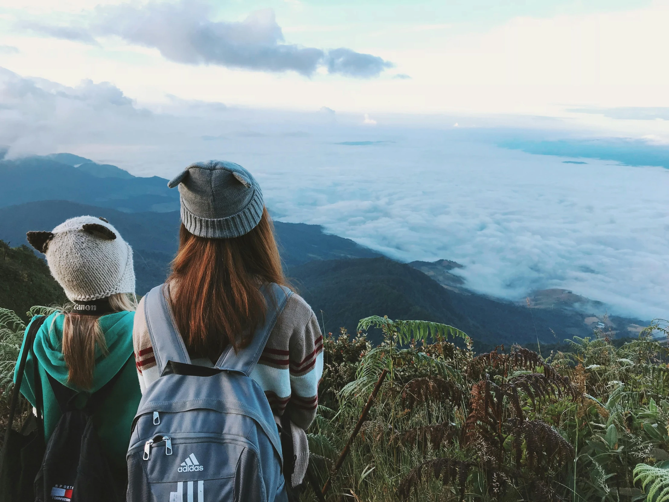 two people overlooking mountains with clouds coming through them