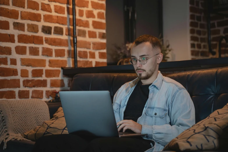 a man using his laptop on a couch in a dimly lit room