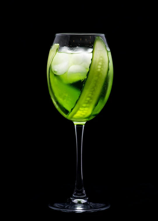a drink is shown in the dark with a cucumber inside