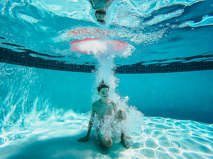 a man sitting under the water in a swimming pool