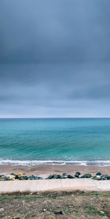 a lone bench sitting on a sandy beach