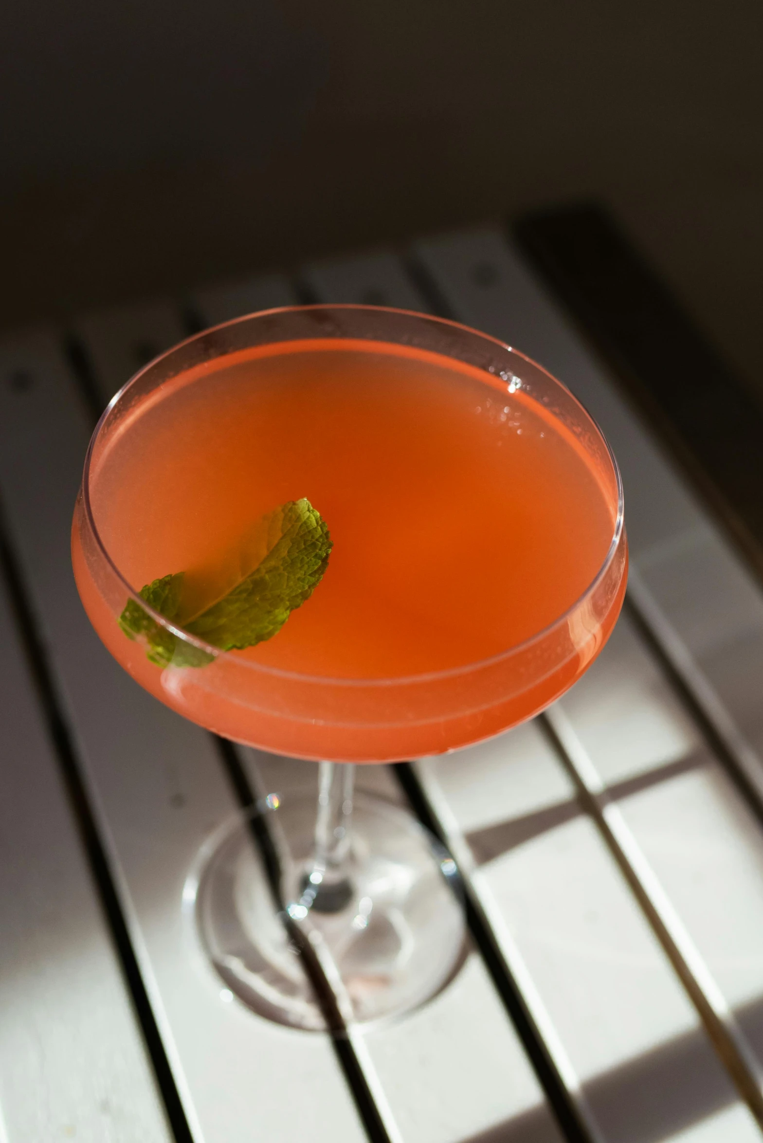 a small orange drink in a coupe glass