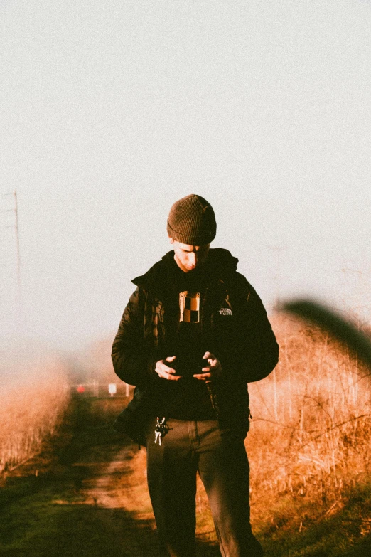 man using cell phone standing near a hill