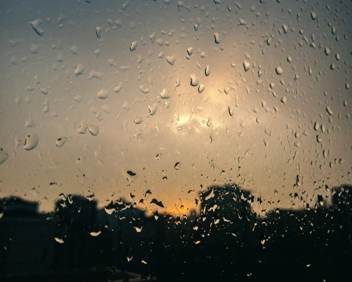 rain on the glass at a window with the sun setting in the background