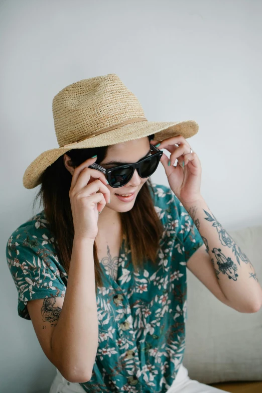 a woman sitting on a couch wearing a straw hat