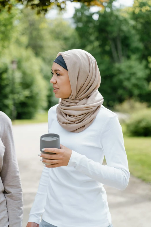 two young women are standing in a park