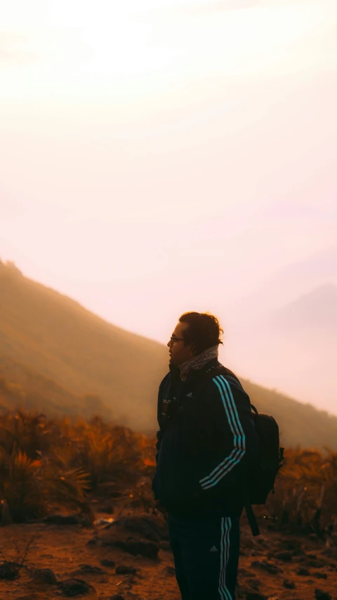 person in the field with backpack, near the mountain