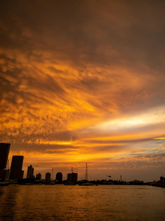 sunset and clouds reflect on the water next to a city