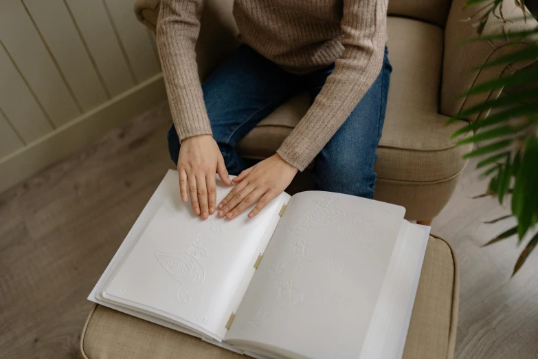 a woman sitting on a couch, reading an open book