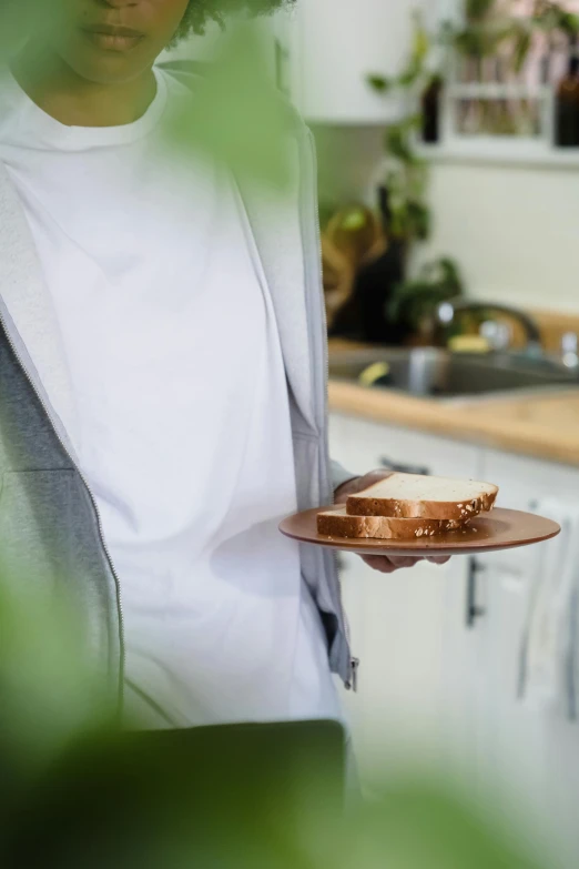 man standing in kitchen holding onto cake with topping on top