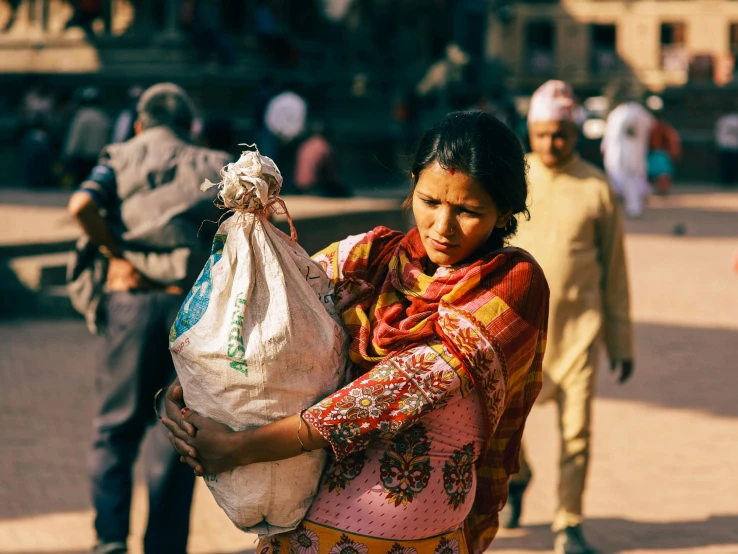 a woman carrying a bag with a pile of stuff in it