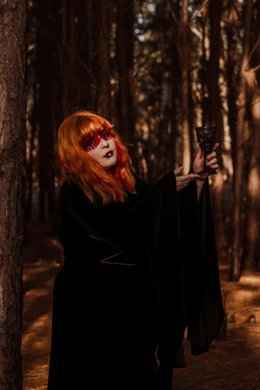 a woman holding up a glass of liquid in the forest