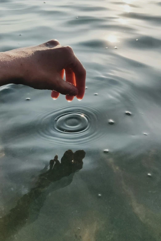 an object floating in water with one hand above the water