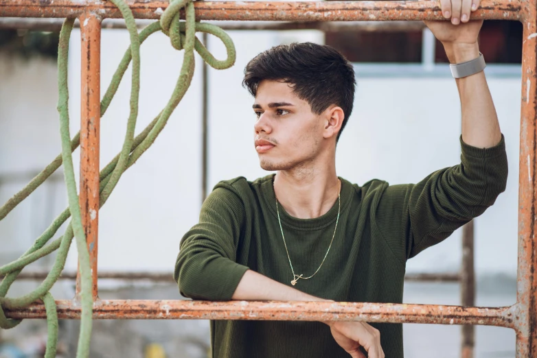 a young man leans on some pipes as he works on a piece of art