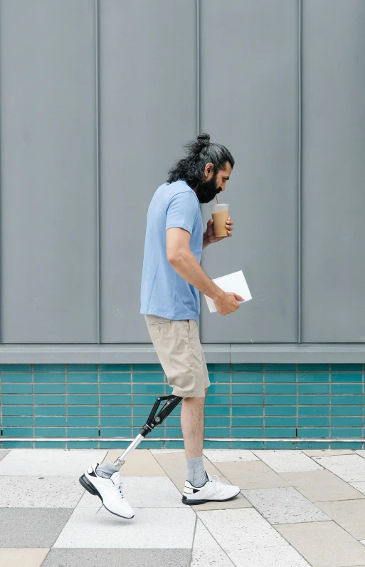 a man walking with a crutch carrying coffee