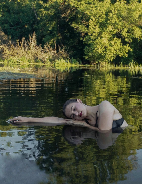a girl in a short swimsuit laying on a body of water