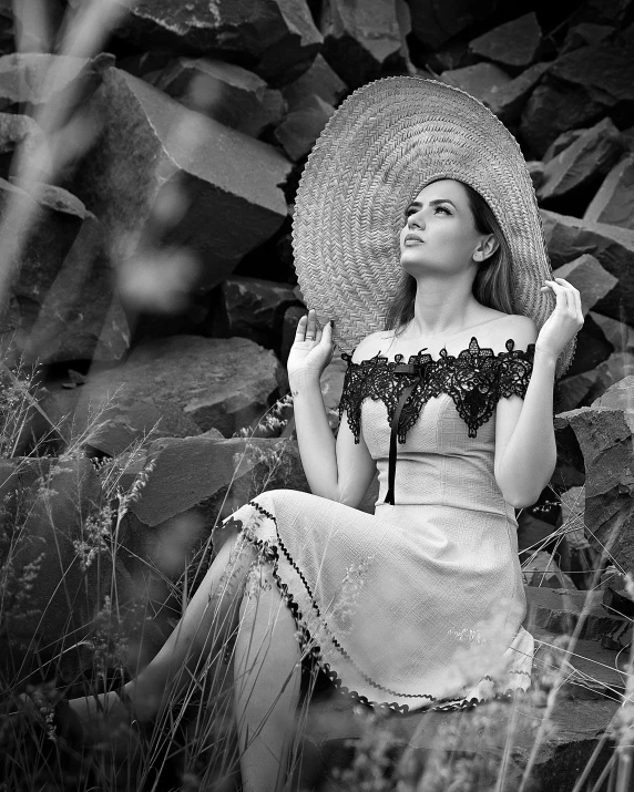 a woman with a large straw hat sitting on top of a field