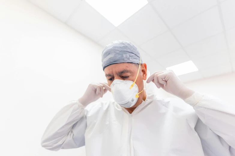 a man in sterile clothes covers his face with surgical clothing