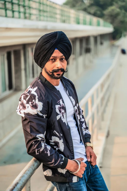 a man with a turban standing next to a fence