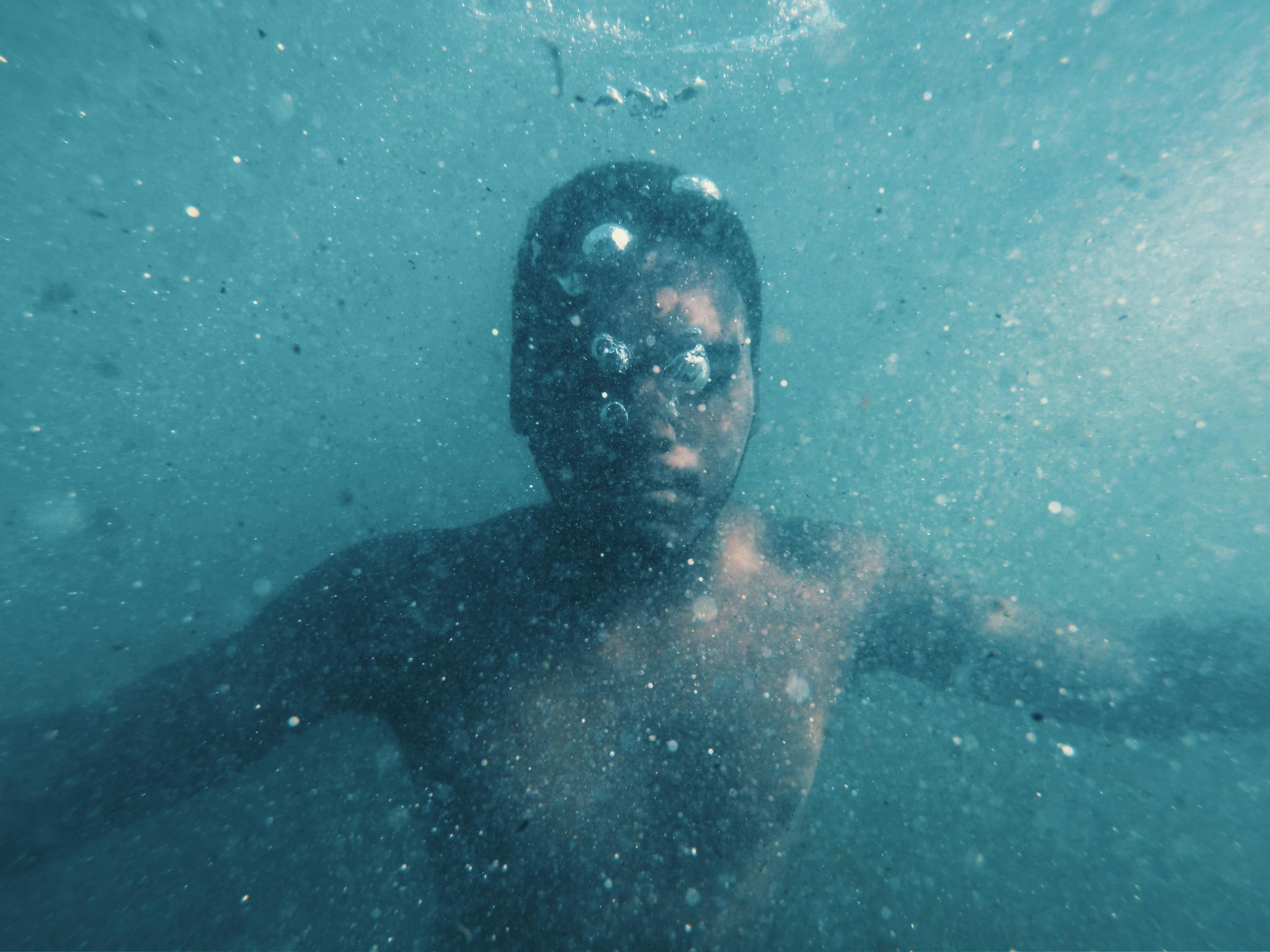 a young man swimming beneath water looking out into the ocean