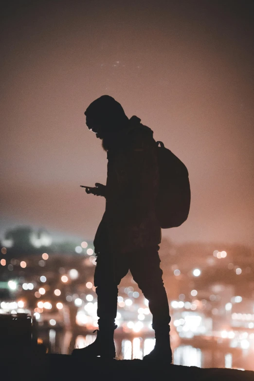 person on top of a mountain at night with lights in the background