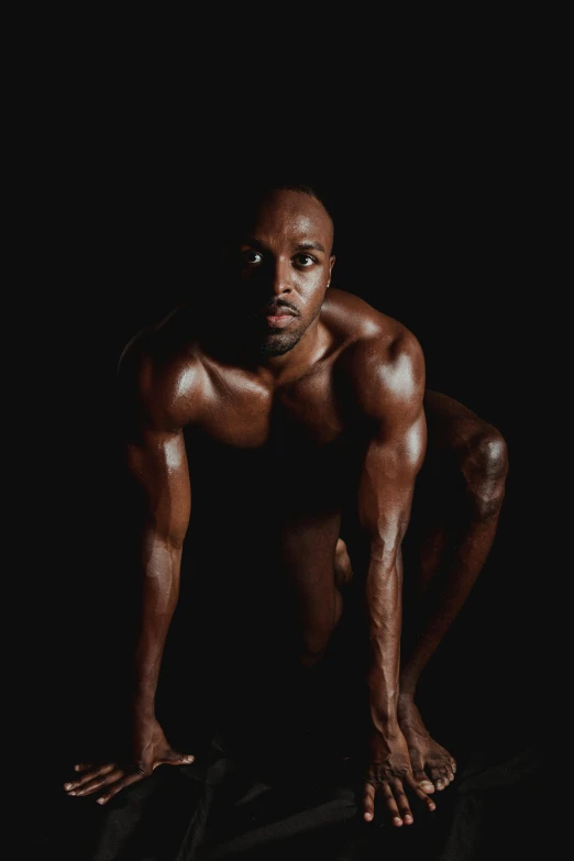 a shirtless man squatting while posing for the camera