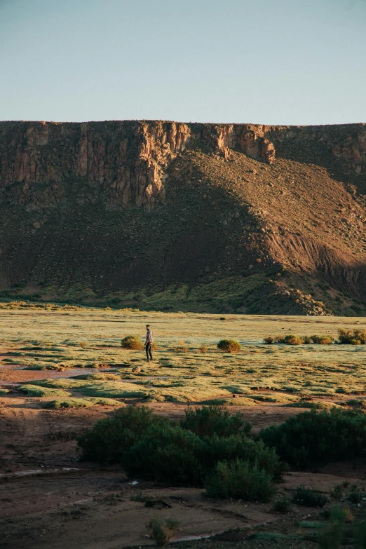 a person walking across the ground towards a mountain