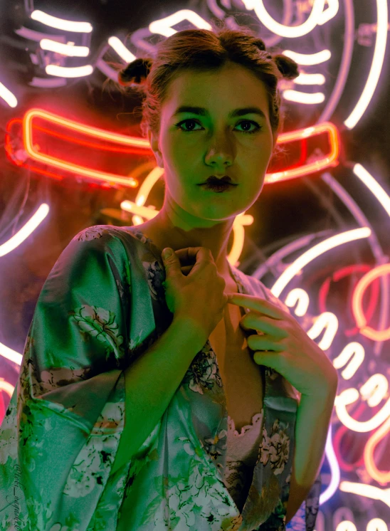 woman in green robe standing next to a colorful neon background