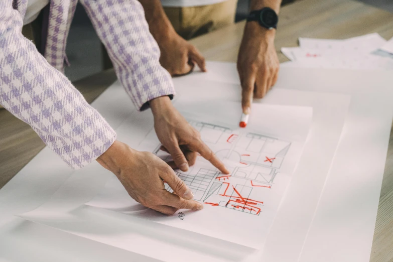 three people working on an architectural project on paper