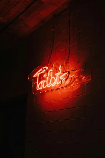 neon sign saying fablot with graffiti writing on a brick wall