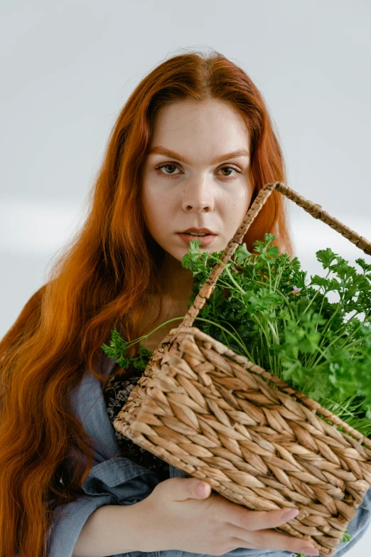 a beautiful young woman holding a basket filled with lots of greens