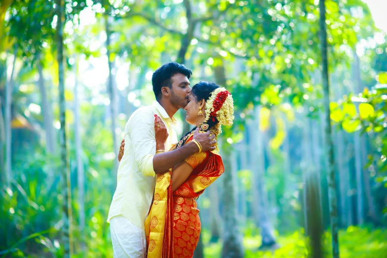 a newlywed couple standing in the middle of some trees