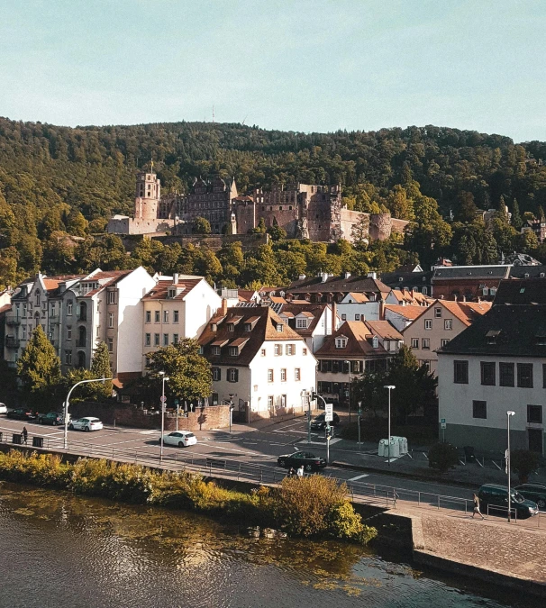 several white buildings sit along the water with a mountain in the background