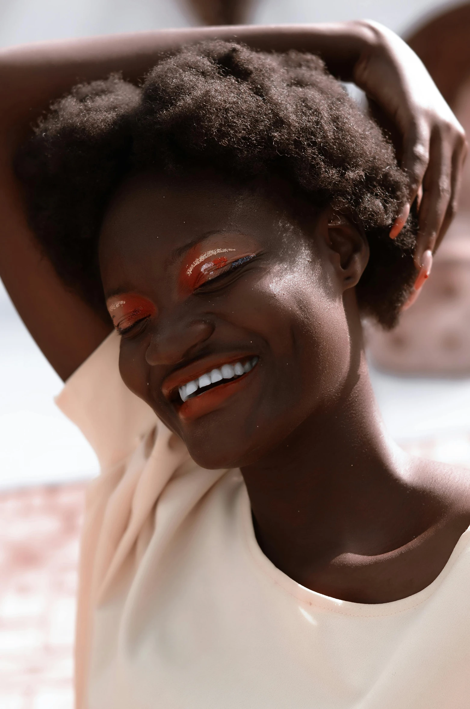 a woman wearing red eye makeup and holding her hair back