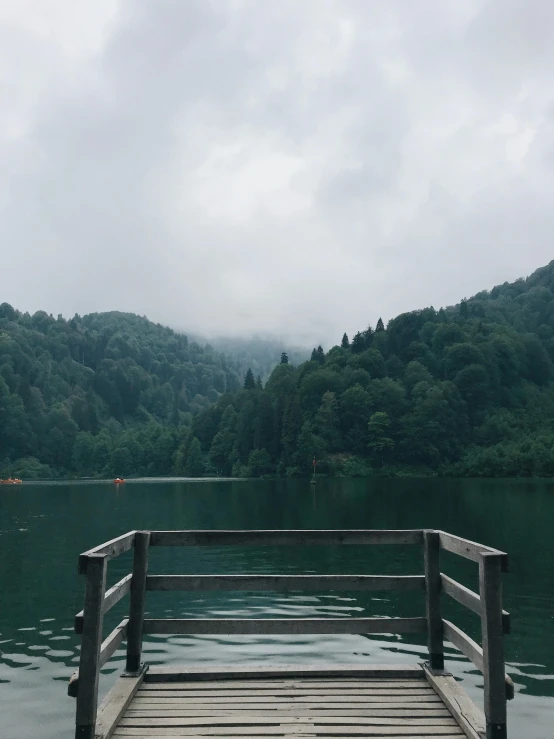 a dock extends out over the water with hills in the distance