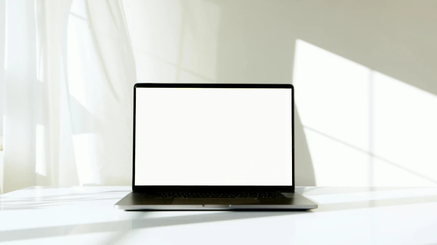 laptop with blank white screen sitting on white table