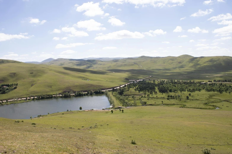 a view of a field near some water and mountains