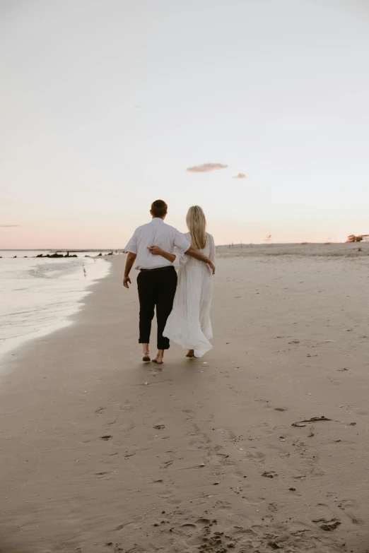 an image of a man and woman walking together on the beach