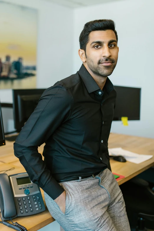 the man stands near the desk in front of the computer