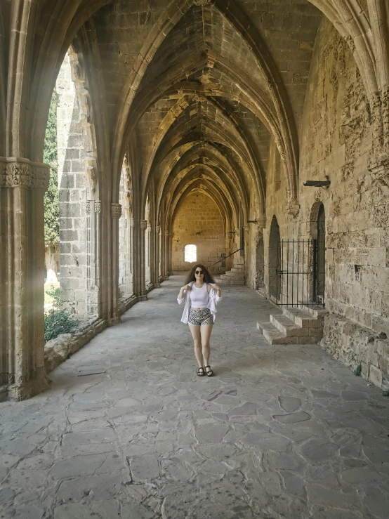 a woman walking down an archway covered in stone