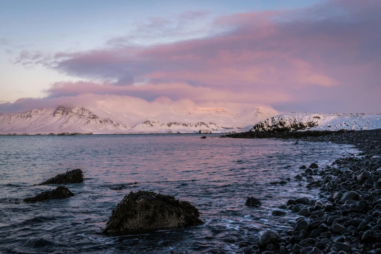 snow covered mountains and mountains rise above the ocean