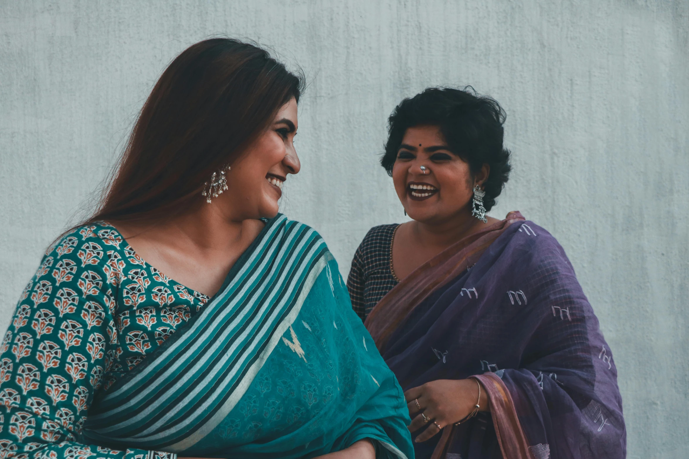 two women in colorful clothing are laughing