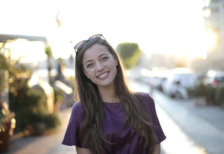 a close - up of a girl in a purple top smiling for a picture