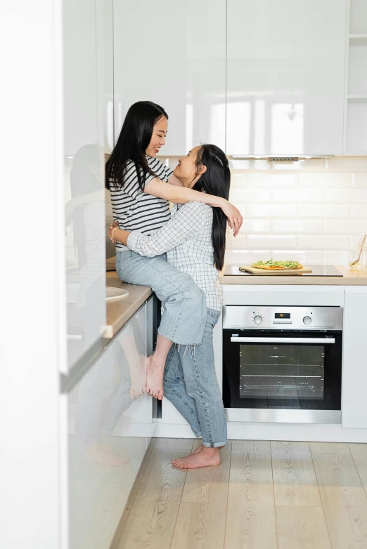 two girls hugging and kissing in the kitchen