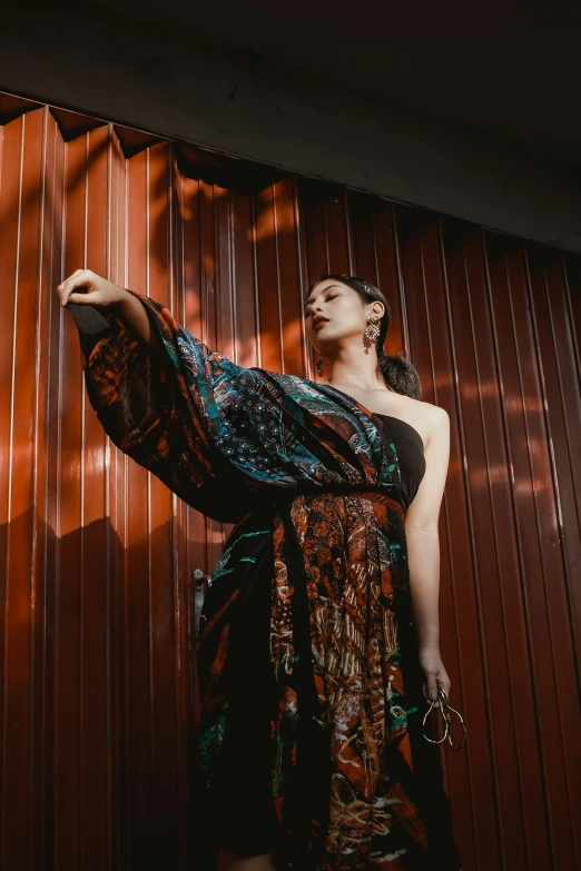 a beautiful woman in a colorful dress standing next to a wall