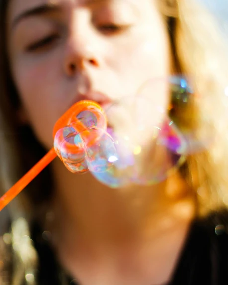 girl blowing bubbles on her tongue by her teeth